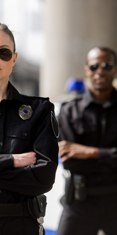 police-officers-with-crossed-arms-looking-at-camera-in-front-of-car.jpg